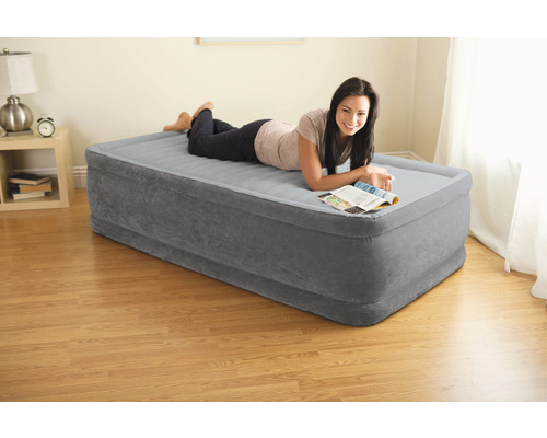Graue Luftmatratze mit einer darauf liegenden Person in einem hellen Raum.