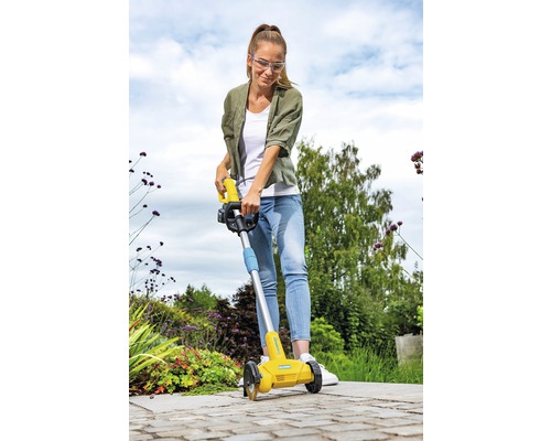 Une femme utilise un coupe-bordures dans le jardin.