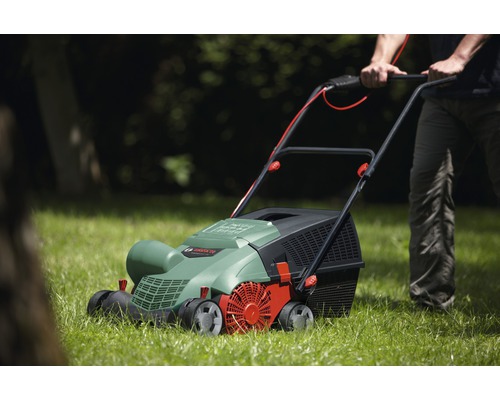 Une personne utilise un scarificateur à gazon dans le jardin.