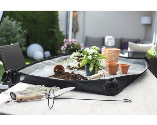 Scène de jardin avec accessoires de plantation, bac à plantes, terreau et plantes sur une table