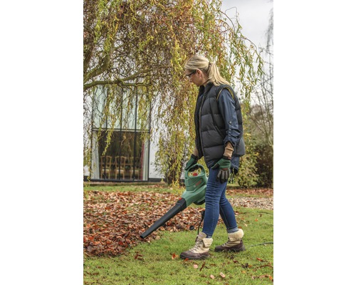 Femme utilisant un aspirateur de feuilles dans le jardin.
