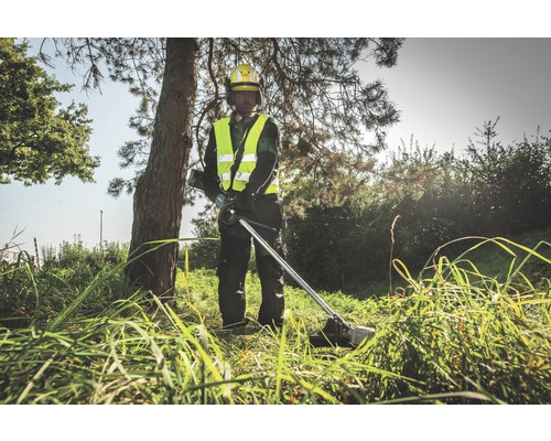 Un homme portant un casque de sécurité jaune et un gilet de sécurité utilise un coupe-bordure dans l''herbe.