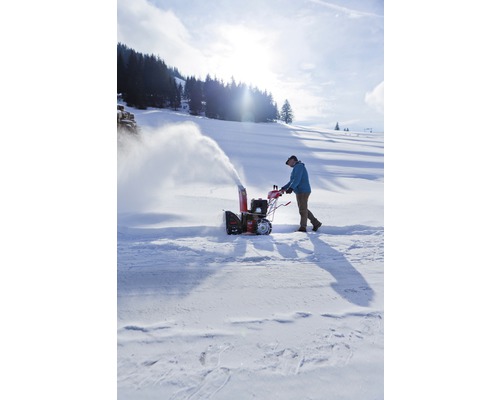 Une personne utilise une fraise à neige dans la neige.