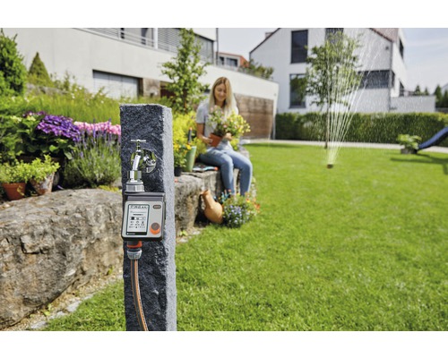 Robinet Gardena avec programmateur d''arrosage et femme avec plante dans le jardin