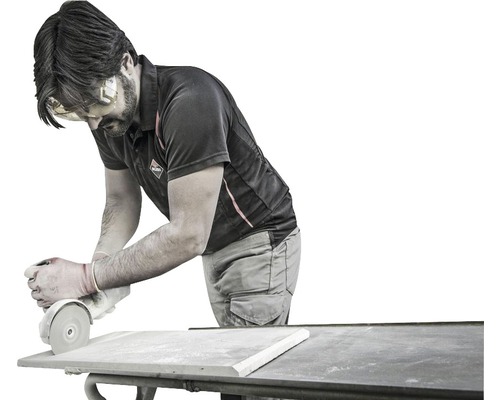 Un homme ponce un carreau avec une meuleuse d''angle sur une table.