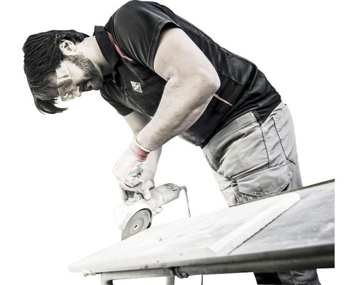 Un homme coupe un carreau avec une meuleuse d''angle