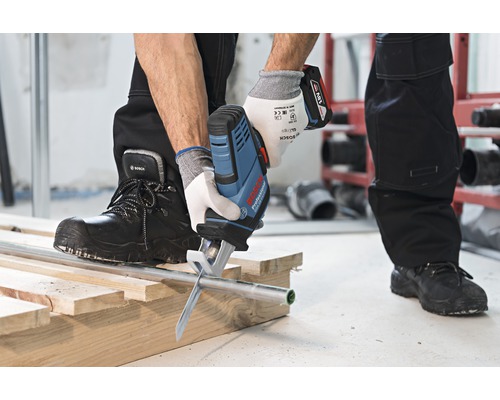 Scie à batterie coupant un tuyau sur une construction en bois.