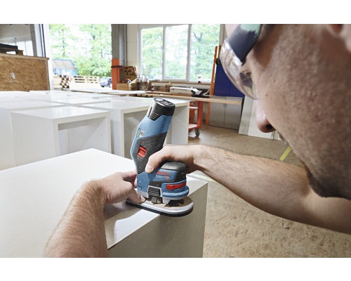 Un homme utilise une ponceuse multifonction sans fil Bosch pour poncer une pièce.