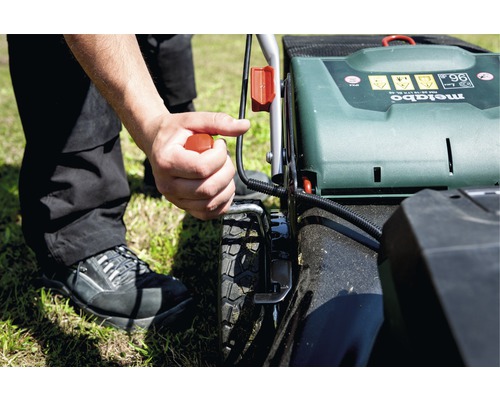 Une personne démarre une tondeuse à gazon de la marque Metabo