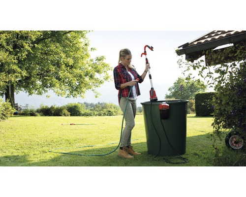 Femme utilisant un arroseur de jardin télescopique pour arroser les plantes du jardin.