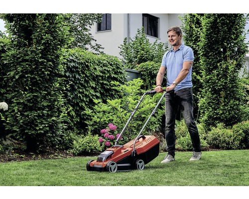 Un homme tond la pelouse avec une tondeuse à gazon dans le jardin.