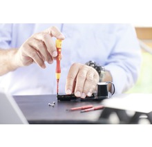Handwerker arbeitet mit Schraubendreher an elektronischem Gerät