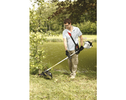 Homme coupant l''herbe au bord d''un lac avec un coupe-bordure