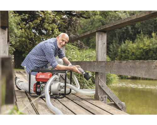 Un homme utilise une pompe de jardin AL-KO sur un pont de bois au bord d''un lac.