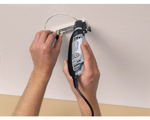 Eine Person schneidet mit einem Dremel Multifunktionswerkzeug ein Loch in eine Decke.