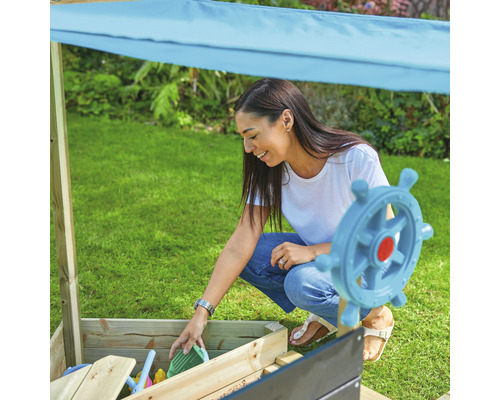 Femme jouant avec des jouets de sable dans un bac à sable avec protection solaire