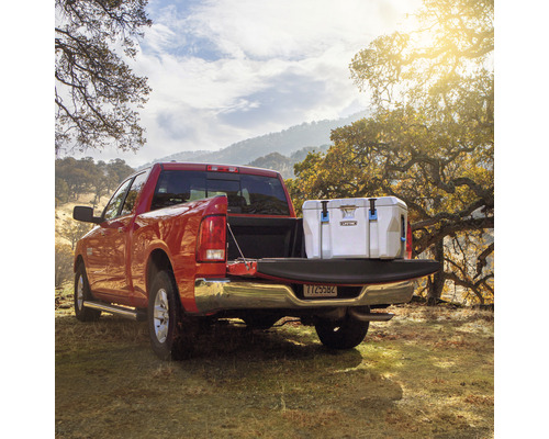 Roter Pickup mit Kühlbox auf der Ladefläche im Gelände.