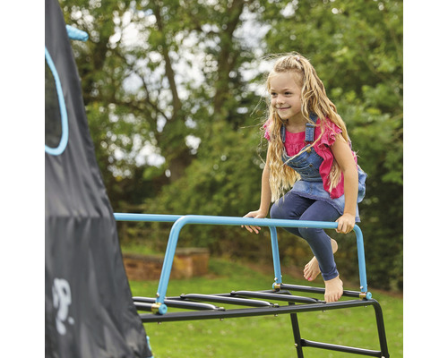 Une fille escalade une cage à écureuil dans le jardin.