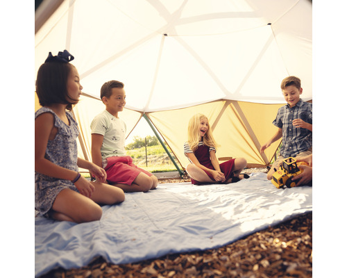 Des enfants jouent dans une tente dôme géodésique sur une couverture bleue.