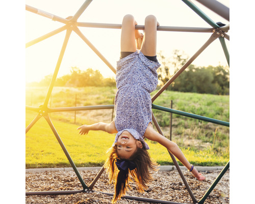 Fille suspendue la tête en bas sur une structure d''escalade extérieure.