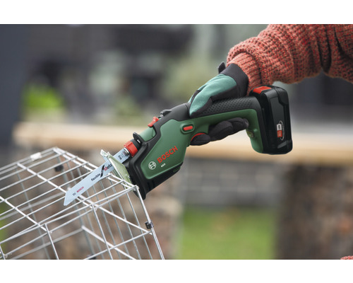 Logo Bosch. Une personne coupe un panier métallique avec une scie sabre sans fil