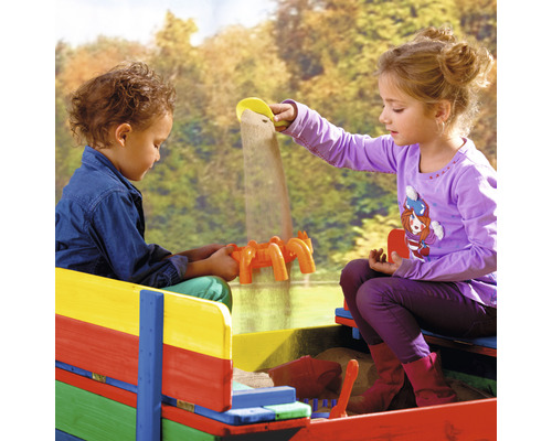 Deux enfants jouent dans un bac à sable coloré avec des jouets de sable.