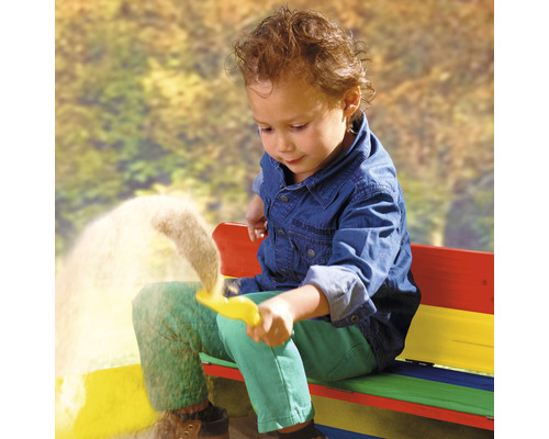 Un enfant joue avec un jouet de sable sur un banc coloré.