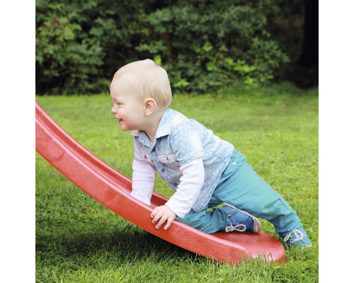 Un enfant en bas âge grimpe sur un toboggan dans le jardin.