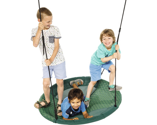 Trois enfants jouent sur une balançoire nid d''oiseau dans le jardin.