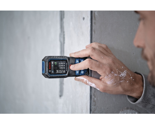 Eine Person benutzt einen Bosch Entfernungsmesser an einer Wand zur Messung.