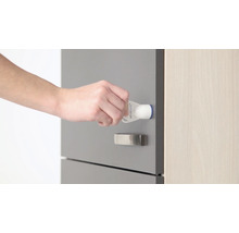 Eine Hand befestigt eine Kindersicherung an einer Schublade.