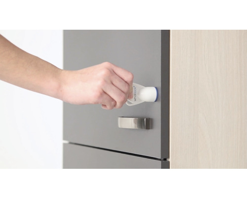 Eine Hand befestigt eine Kindersicherung an einer Schublade.