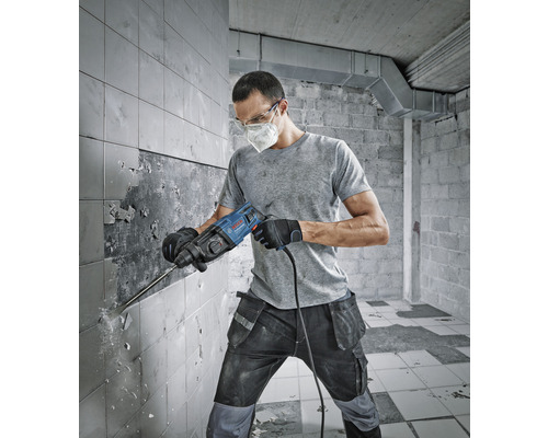 Un homme travaille avec un marteau-piqueur sur un mur carrelé