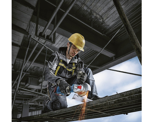 Arbeiter mit Schutzhelm und Winkelschleifer beim Metallschneiden auf einer Baustelle