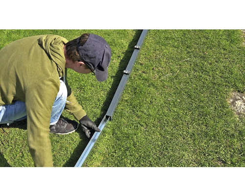 Eine Person montiert eine Metallkonstruktion im Garten.