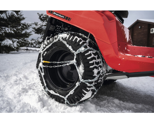 Rad eines Rasentraktors mit Schneeketten im Winter