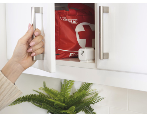 Geöffnete weisse Küchenschranktür mit Verbandskasten im Inneren
