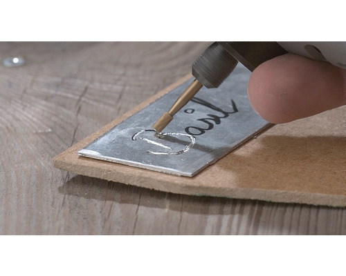 Outil de gravure marquant une plaque métallique avec le mot ''Basil''