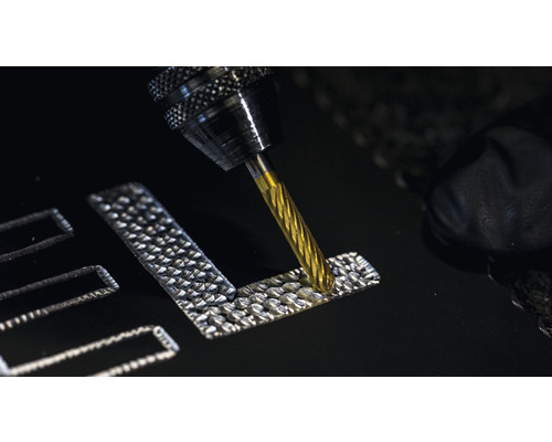 Un outil de fraisage grave un motif dans un matériau.