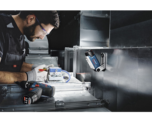 Artisan au travail avec une visseuse sans fil, une lampe et des outils