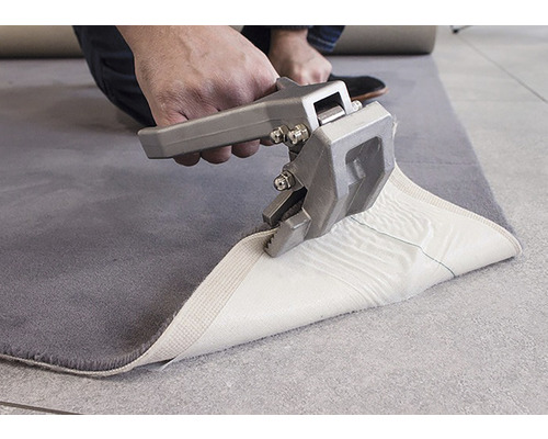 Coupe-tapis en utilisation sur un tapis gris