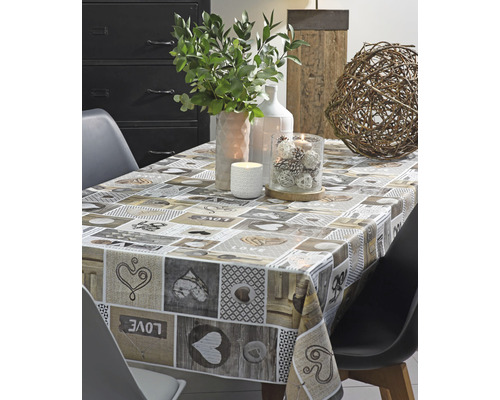 Table dressée avec une nappe à motifs de cœurs et des objets de décoration tels que des bougies et des plantes.