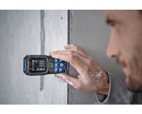 Eine Person benutzt einen Laser-Entfernungsmesser von Bosch zur Messung.