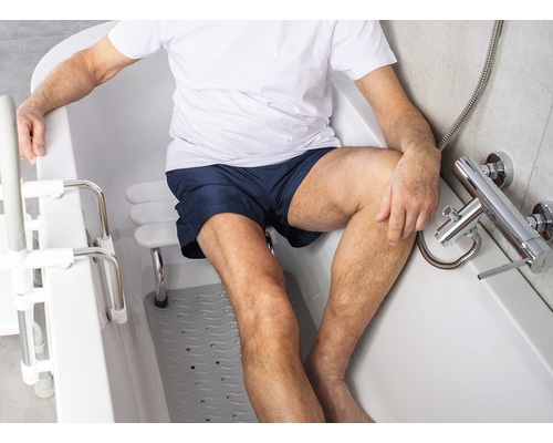 Un homme est assis dans une baignoire avec aide à l''entrée et siège de bain