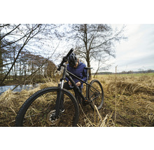 Mann mit Helm repariert ein Mountainbike in der Natur.