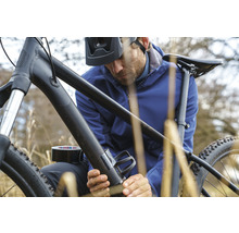 Mann befestigt Flaschenhalter mit Klebeband an einem Fahrrad