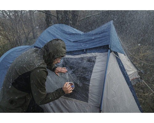 Person reinigt Zeltfenster bei Regenwetter.
