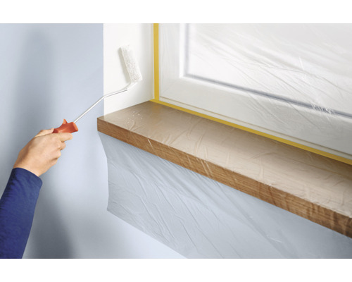 Wand streichen mit Farbroller, Fenster und Fensterbank abgedeckt mit Folie und Klebeband.