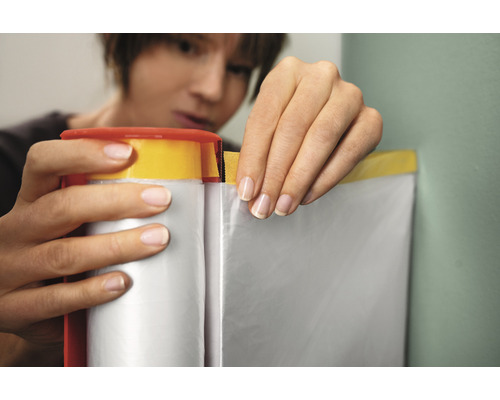 Frau verwendet Abdeckband mit Folie zum Schutz von Oberflächen beim Malen