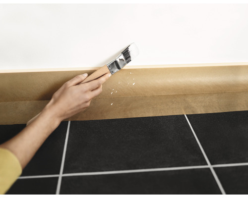 Streichen einer Wand mit Pinsel und Abdeckband zum Schutz des Bodens